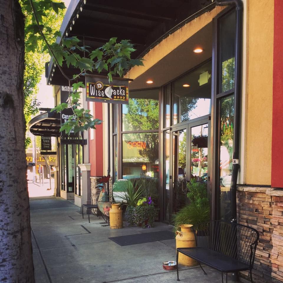 The WiseCracks Cafe storefront on 3rd Street in downtown Corvallis, with its hanging sign, OPEN sign, potted plants and sidewalk seating